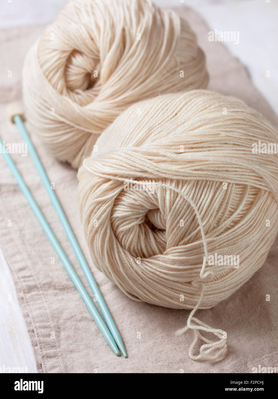 Kugeln aus Garn und Stricknadeln auf Leinen Serviette Stockfoto