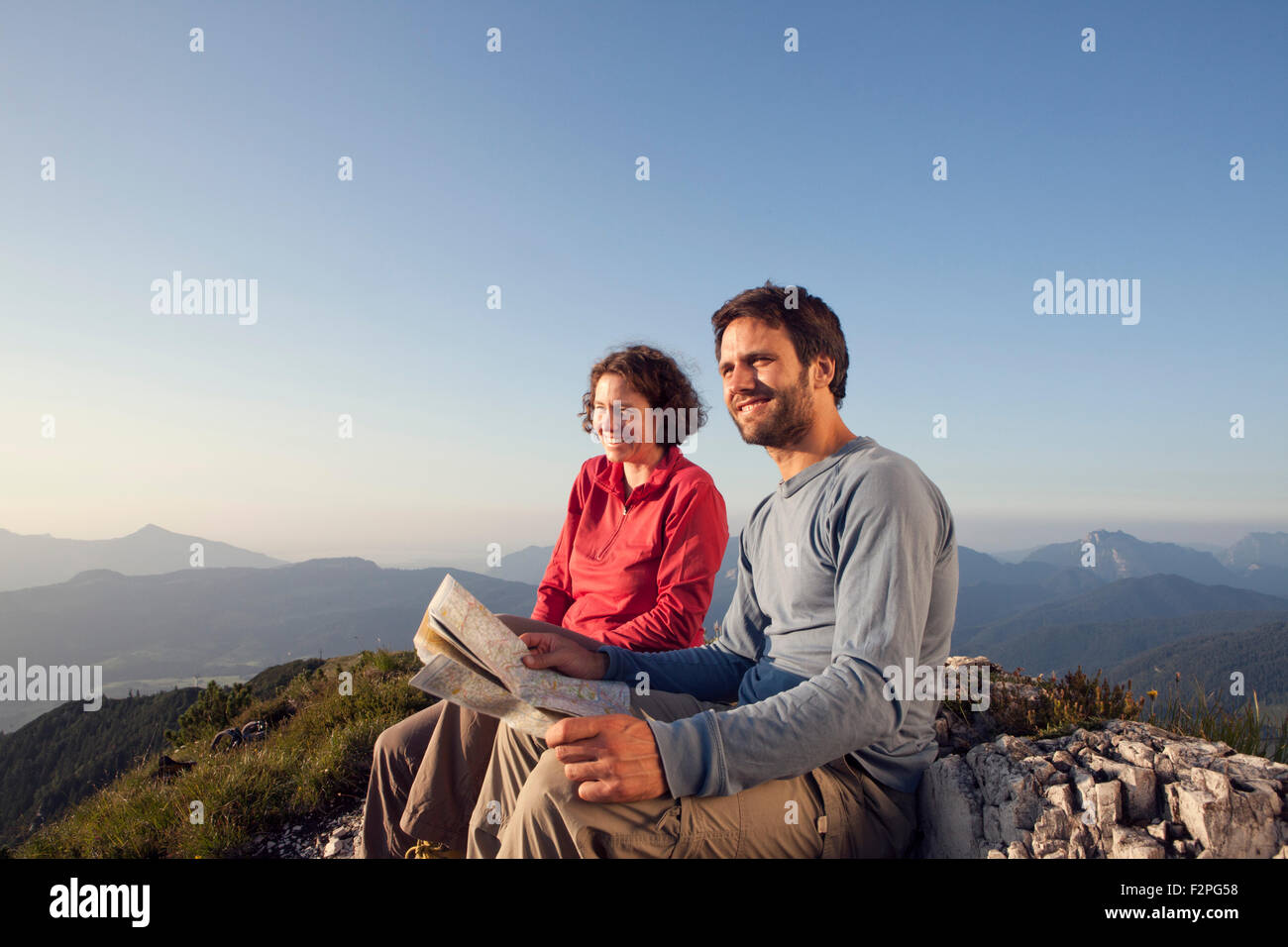 Österreich, Tirol, Unterberghorn, zwei Wanderer sitzen mit Karte in alpiner Landschaft Stockfoto