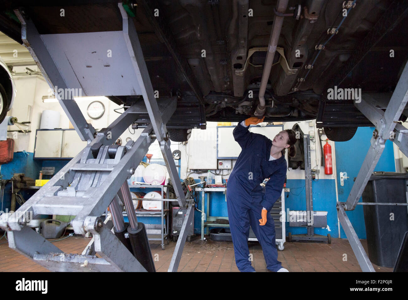 Junge Frau arbeiten in Werkstatt, Überprüfung von Auto auf Hebebühne steht Stockfoto