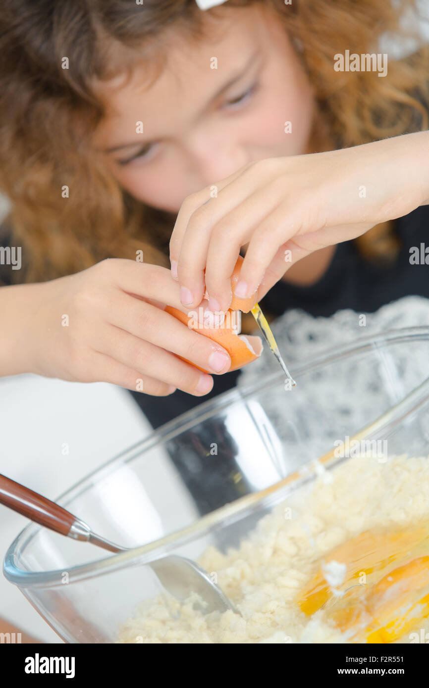Kind brechen Ei in Schüssel Stockfoto