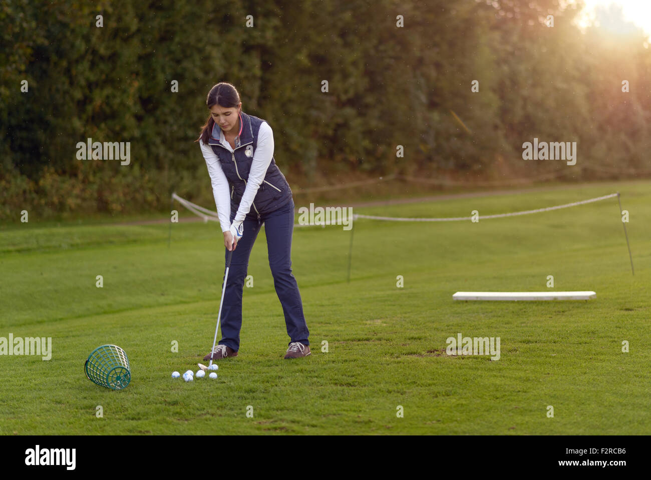 Golfspielerin stehen auf der driving Range am späten Nachmittag am Tag, für den nächsten Schlag konzentrieren Stockfoto