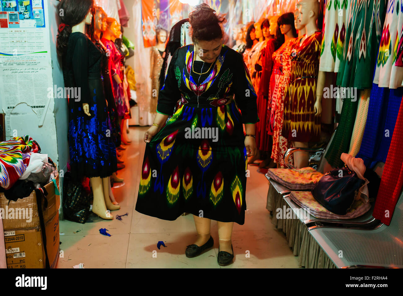 Kashgar, Chinas Xinjiang Uygur Autonome Region. 23. Sep, 2015. Eine Frau versucht auf ihre neuen Kleider in einem Shop in Kashgar, Nordwesten Chinas Xinjiang Uygur Autonome Region, 23. September 2015. Örtlichen Muslime für die bevorstehende Corban Festival Urlaub, auch bekannt als Eid al-Adha oder das Opferfest, auf verschiedene Weise zubereitet. Kashgar, die westlichste Stadt Chinas, war das Zentrum der Uygur Zivilisation seit Jahrhunderten ein Ort, wo Menschen zusammen kamen, um Handel und islamischen Lernens auf die Karawanenwege aus Europa und Persien nach China zu verbreiten. © Zhang Cheng/Xinhua/Alamy Live-Nachrichten Stockfoto