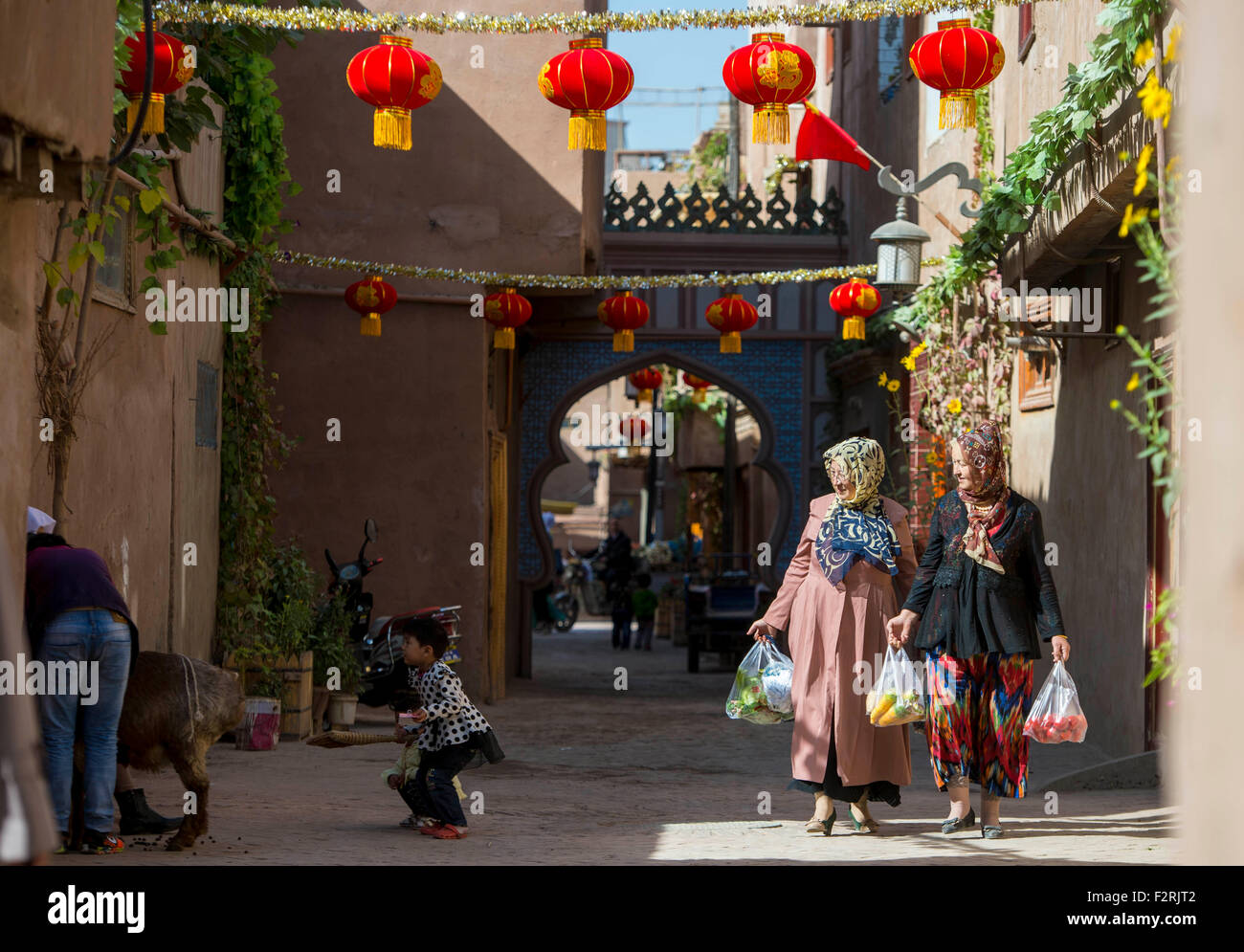 Kashgar, Chinas Xinjiang Uygur Autonome Region. 23. Sep, 2015. Frauen, die Gemüse gekauft haben gehen vorbei an ihre Nachbarn mit einem Schaf in Kashgar, Nordwesten Chinas Xinjiang Uygur Autonome Region, 23. September 2015 zu tun. Örtlichen Muslime für die bevorstehende Corban Festival Urlaub, auch bekannt als Eid al-Adha oder das Opferfest, auf verschiedene Weise zubereitet. Dieses Jahr fällt das Corban Festival am 24. September. © Jiang Wenyao/Xinhua/Alamy Live-Nachrichten Stockfoto