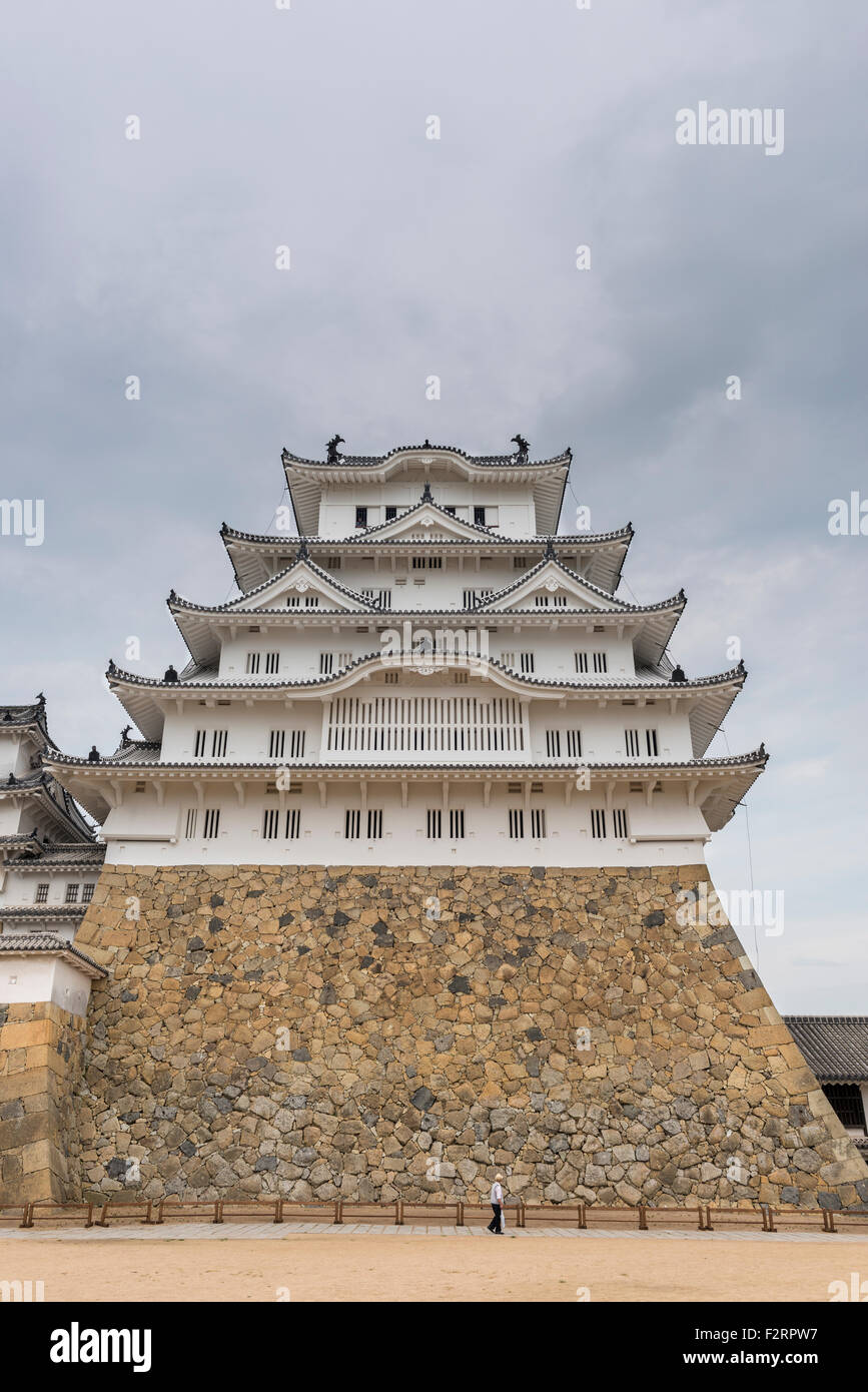 Der Hauptturm der Burg Himeji, einer von Japans UNESCO Weltkulturerbe-Stätten mit einem Touristen vor für Skala Stockfoto