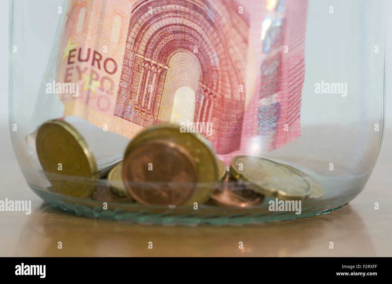Euro-Banknoten und Münzen in einem Glas Stockfoto