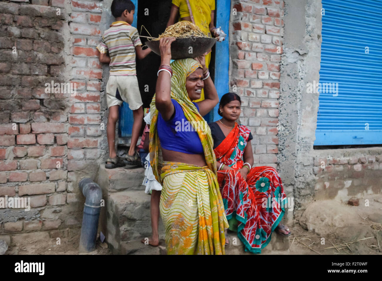 Eine Frau, die vor einem Haus am Stadtrand von Gaya, Bihar, Indien, Lebensmittel auf dem Kopf trägt. Stockfoto