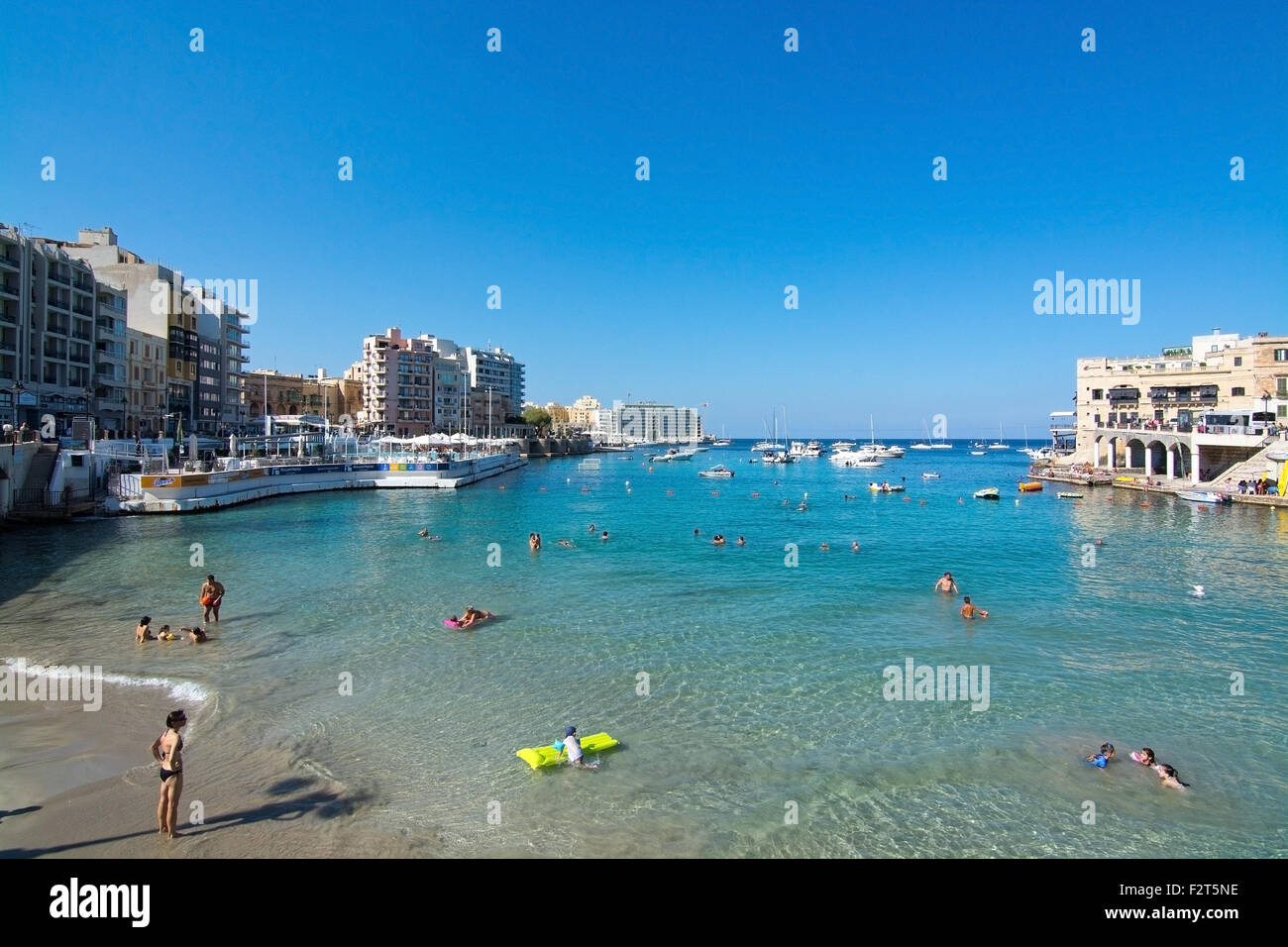 Balluta Bay Strand mit Schwimmer, Stadtgebäude, festgemachten Boote und Mittelmeer Horizont an einem sonnigen Sommertag Stockfoto