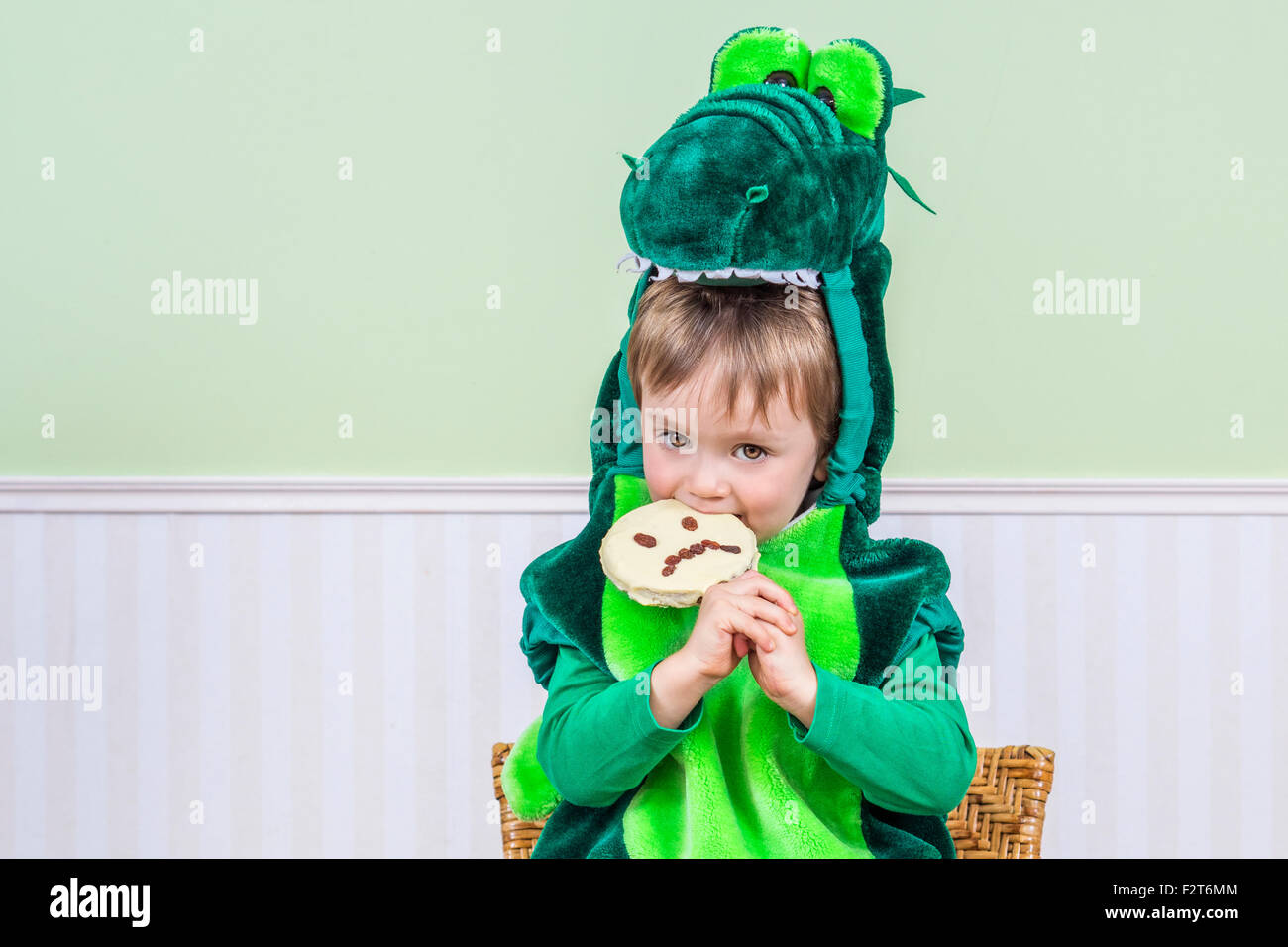 Entzückender kleine Junge in einem Anzug Krokodil isst einen Halloween-cookie Stockfoto