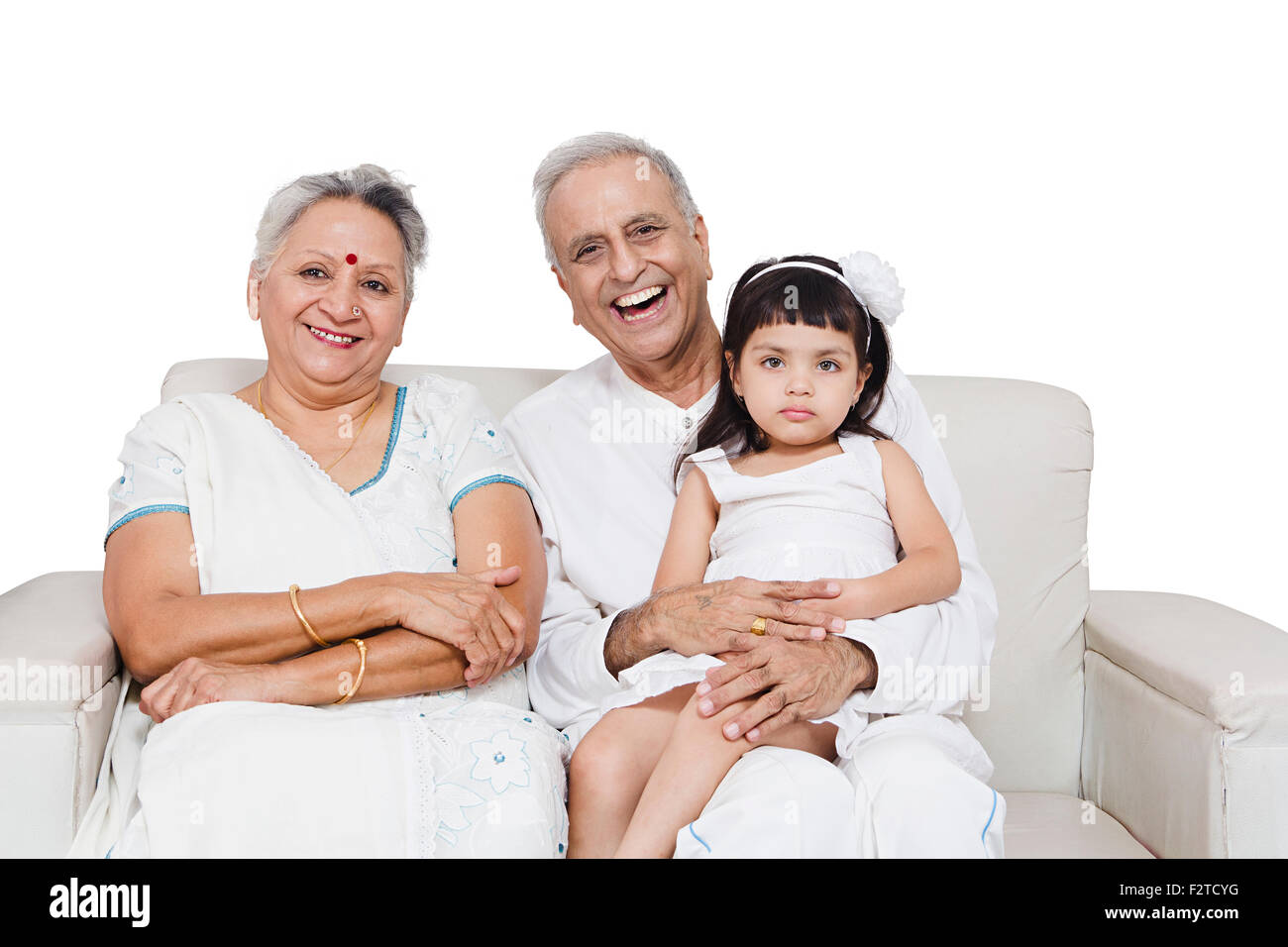 3 indische Großeltern und Enkeltochter sitzen sofa Stockfoto
