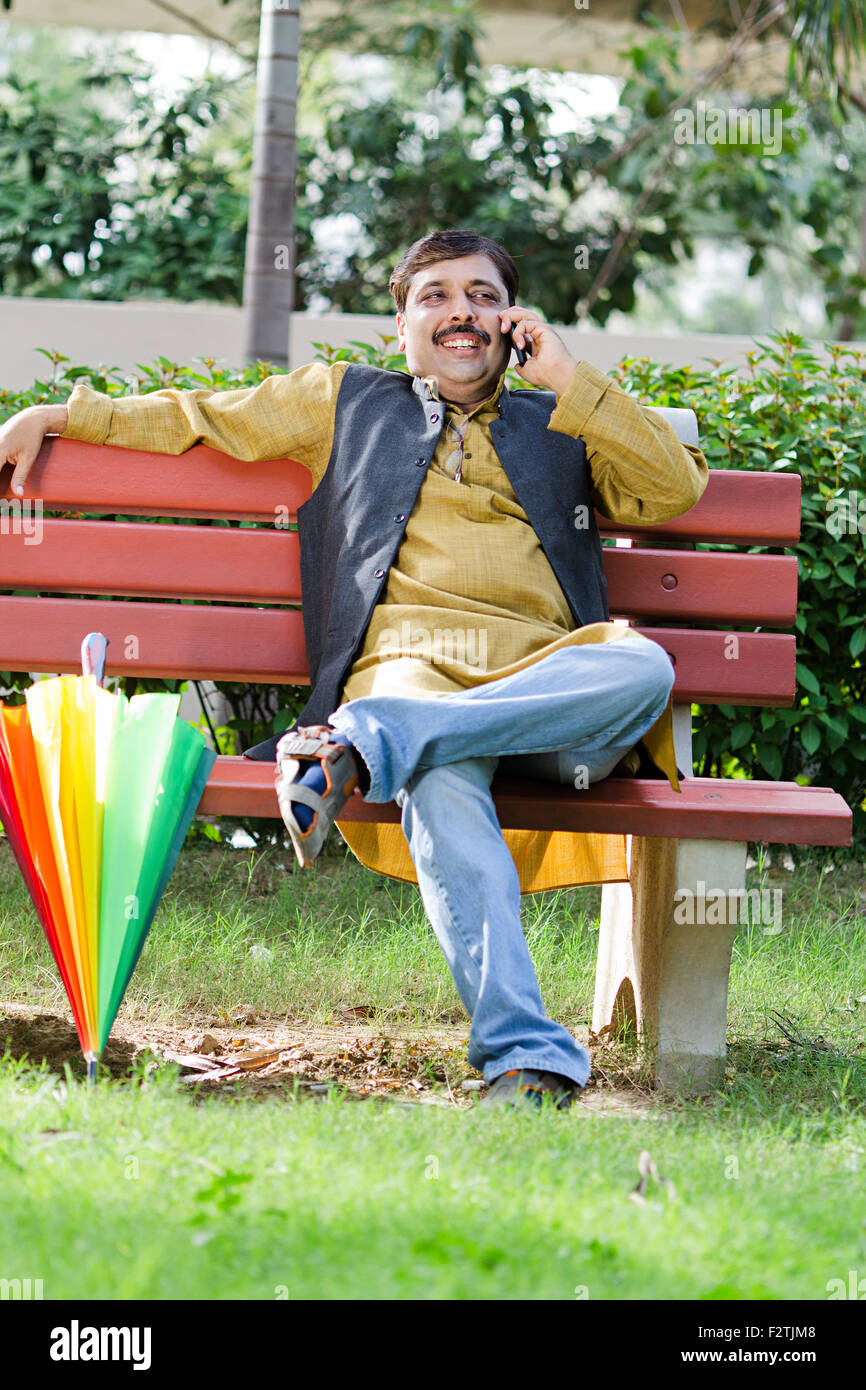 1 indische erwachsenen Mannes sitzen Parkbank Handy im Gespräch Stockfoto