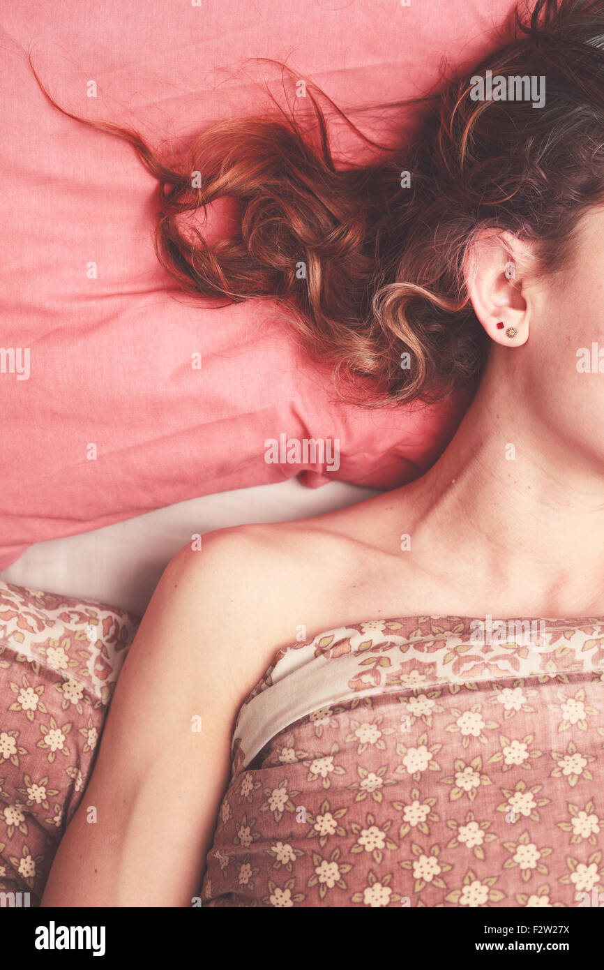 Junge Frau mit ihrem Haar, verstreut über das Kissen im Bett liegend Stockfoto