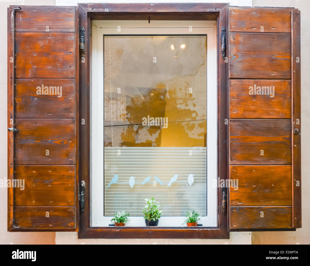 ein schönes Fenster mit offenen braunen Fensterläden aus Holz Stockfoto
