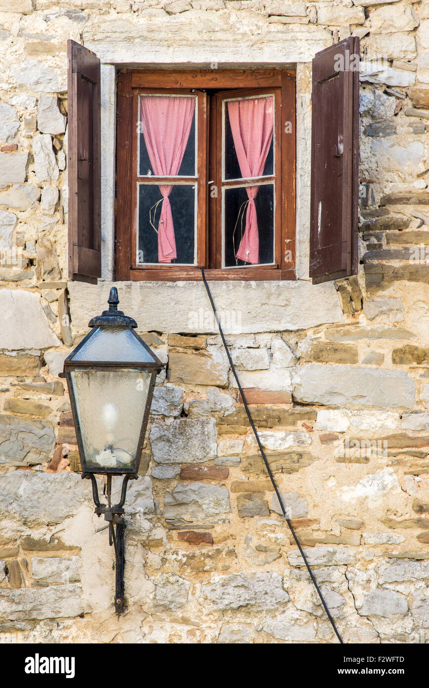 ein schönes Fenster mit offenen braunen hölzernen Fensterläden und Vorhänge Stockfoto