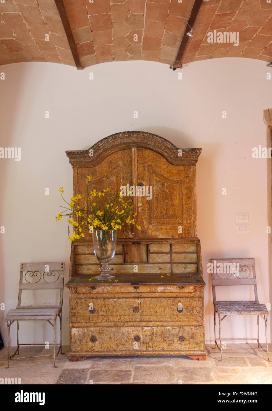 Vase mit gelben Blüten auf antike Kommode in italienischen Land Halle Stockfoto