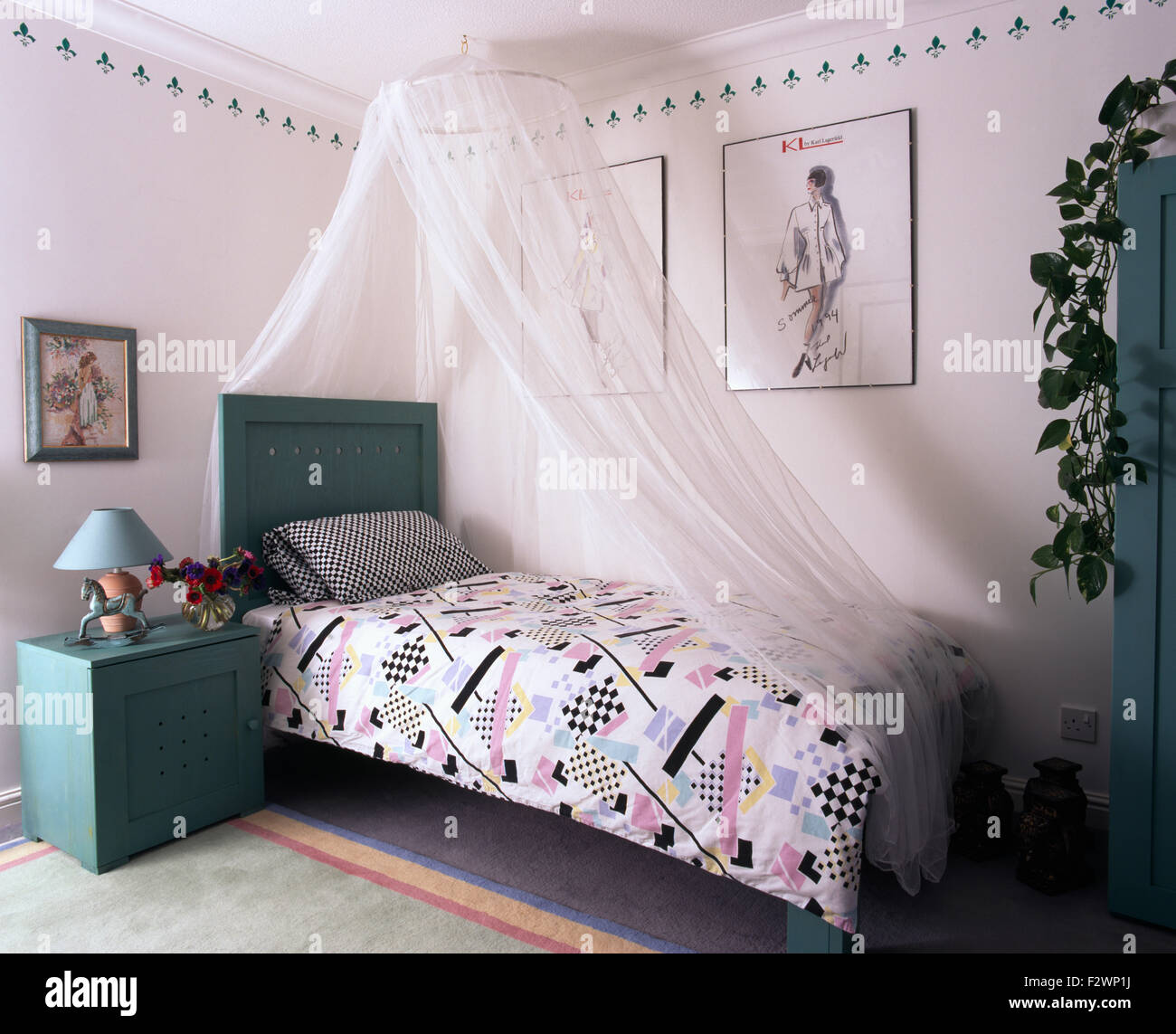 Weißen Voile Vorhänge oben lackiert Einzelbett mit abstrakten gemusterten Bettdecken in neunziger Jahre Schlafzimmer Stockfoto