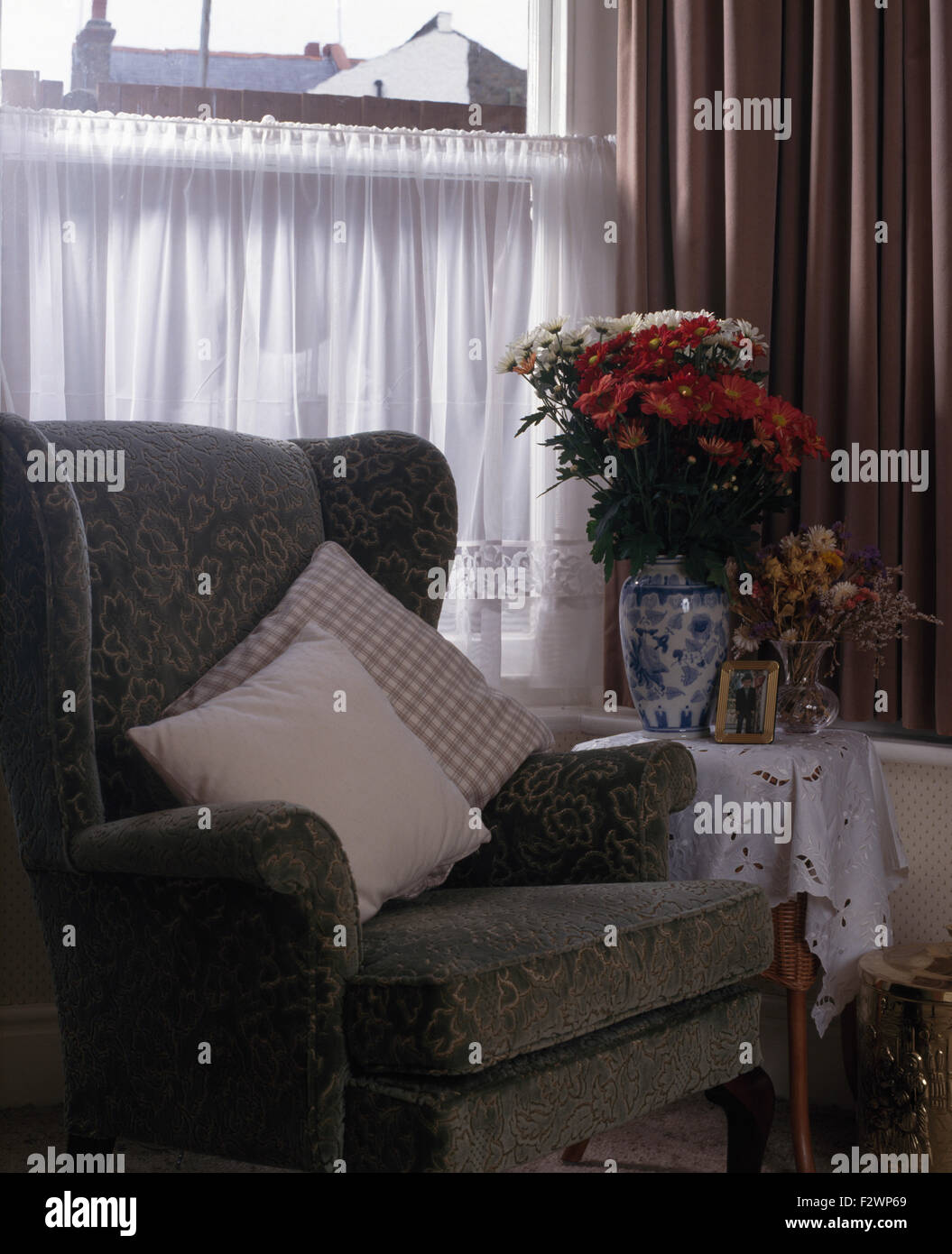 Graue Polsterstuhl vor Fenster mit einem Wshite Netto-Café Vorhang Stockfoto