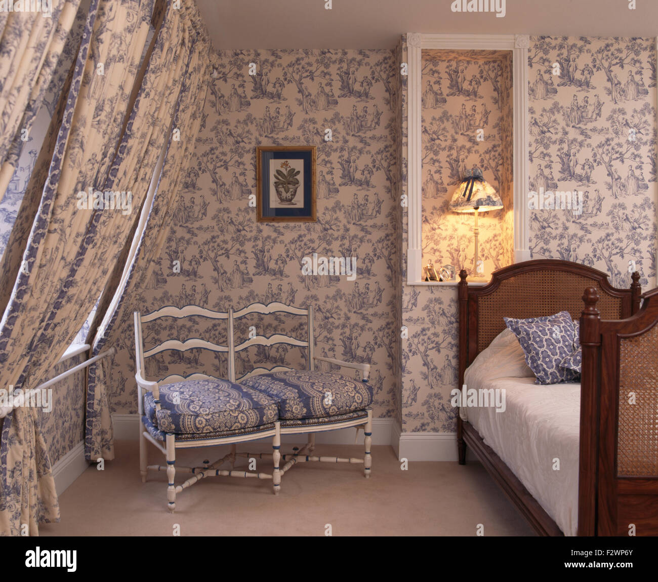 Blaues Toile-de-Jouy-Tapeten und passende Vorhänge im Schlafzimmer Stadthaus mit einem weißen Holzsofa Stockfoto