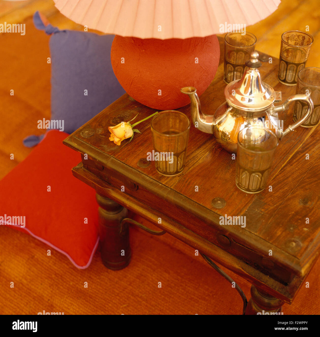 Nahaufnahme einer vergoldeten marokkanische Teekanne mit Tee Gläser auf einem indonesischen Stil Couchtisch Stockfoto