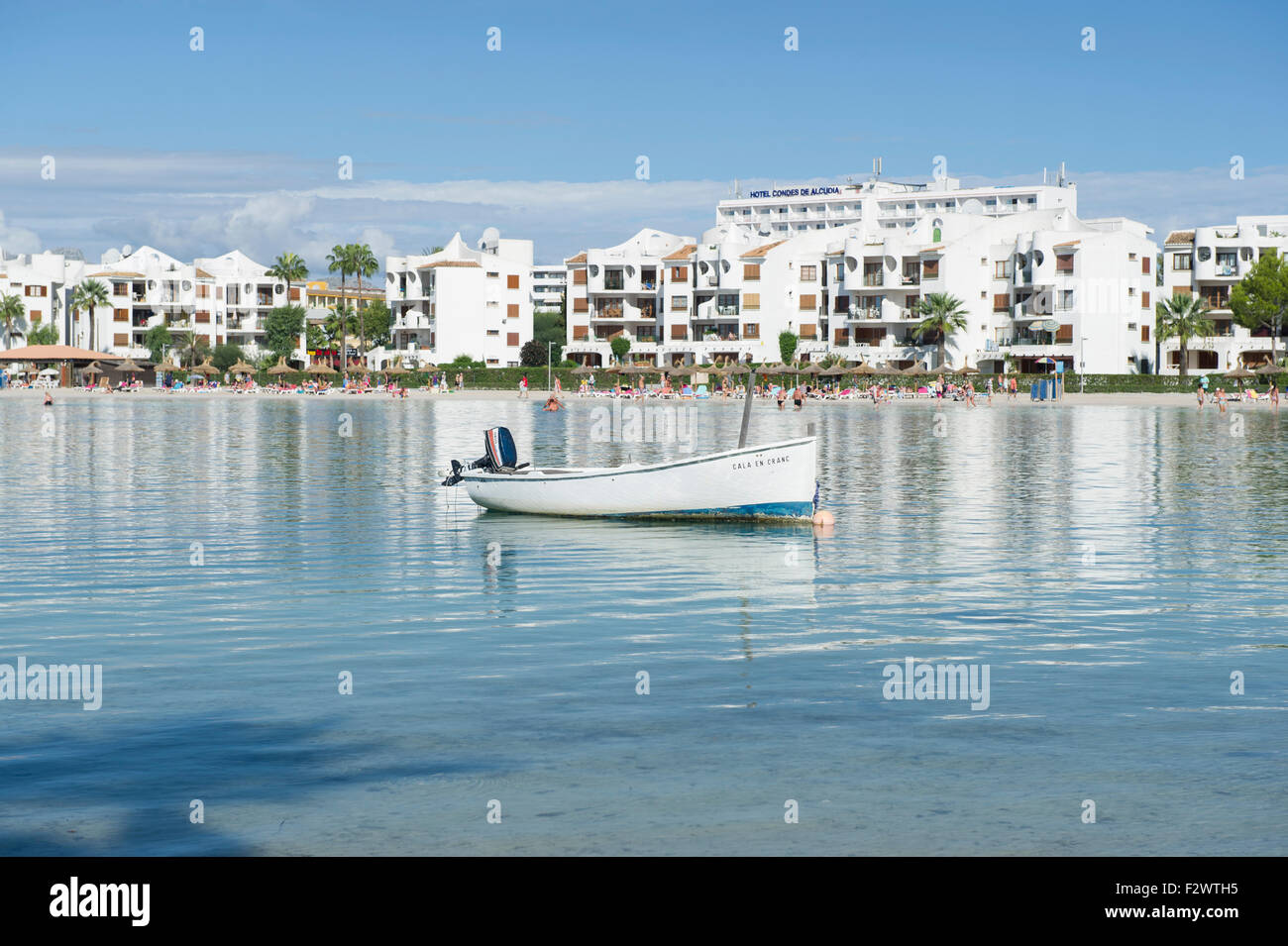 Ein kleines Boot in der Bucht am Hafen d'Alucida in Mallorca(Majorca) mit dem Hintergrund der Touristen und Hotels entlang der Strand Stockfoto