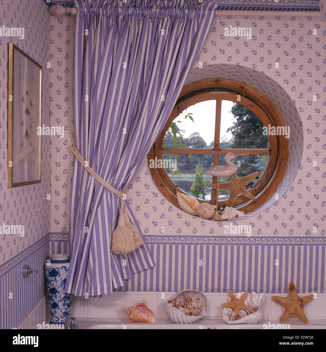 Blau gestreifte Vorhänge am runden Fenster in der neunziger Jahre Bad Stockfoto