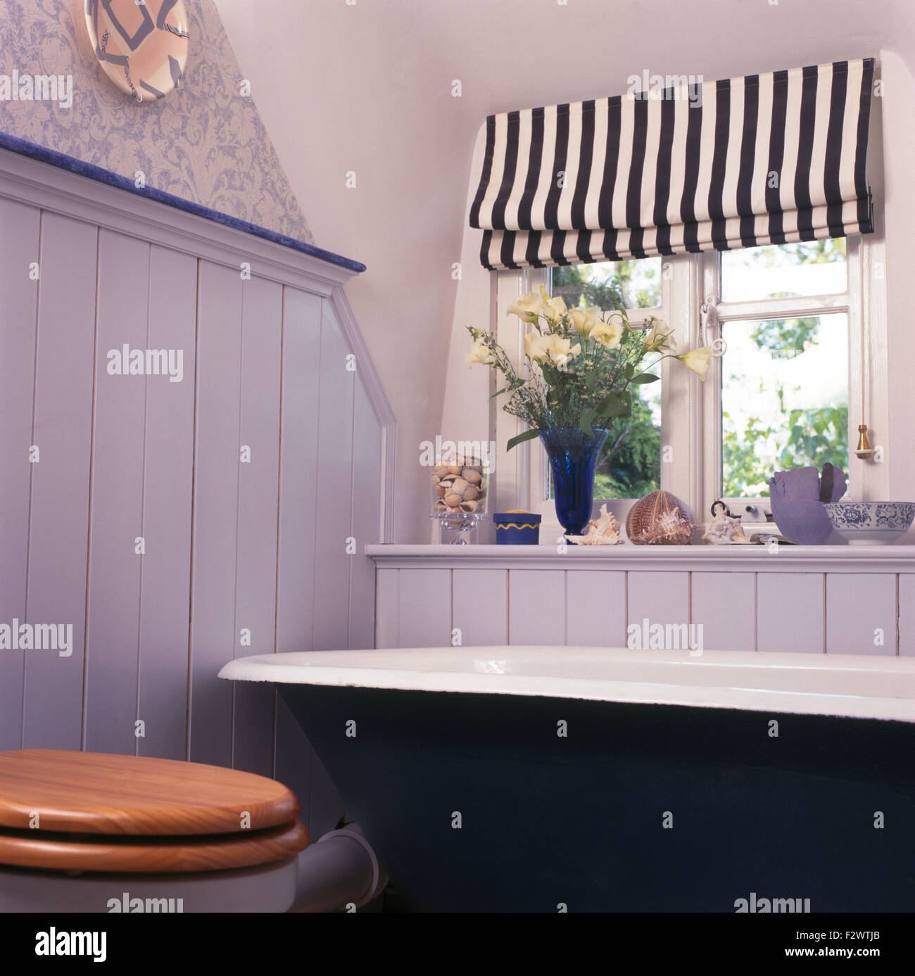 Schwarz + weiß gestreiften Blind auf Fenster oben roll Top Bad im blassen blauen Zunge + Nut verkleidete Badezimmer Stockfoto
