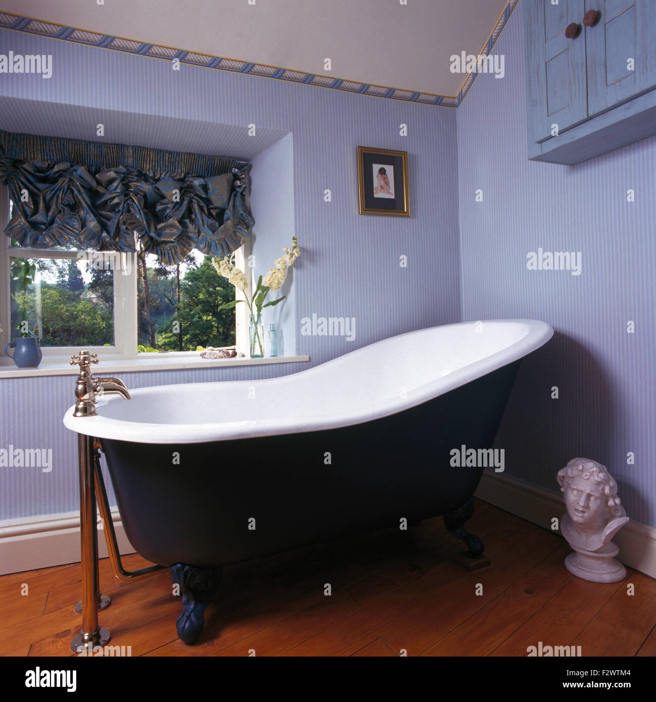 Roll Top Bad in neunziger Jahre Bad mit blau gestreifte Tapete und ein Schwalbenschwanz-Blind Stockfoto