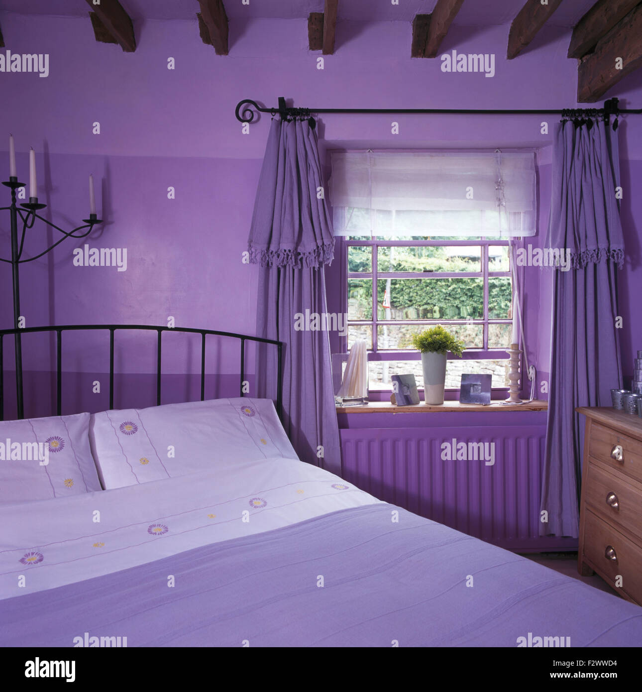 Ein lila unter dem Motto der neunziger Jahre Schlafzimmer mit hellen lila Vorhängen und tief lila Wände Stockfoto