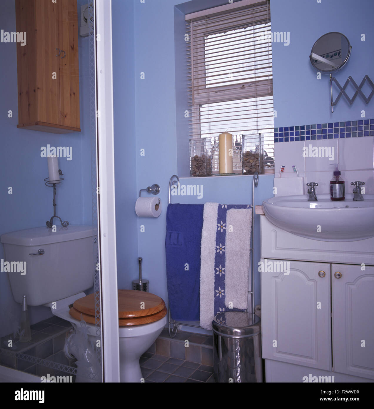 Jalousie am Fenster in kleinen blauen Bad mit Wand montierten Becken Stockfoto