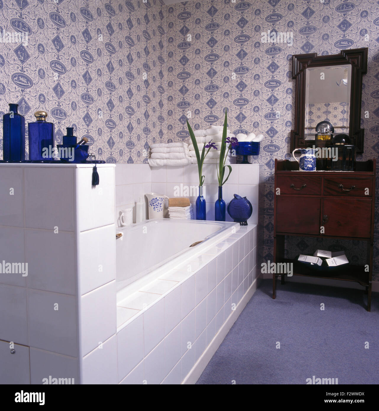 Blaue + weiße Tapete in traditionellen Bathrioom mit antiken Waschtisch neben Bad mit weißen Fliesen Verkleidung Stockfoto