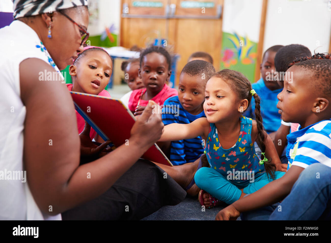 Lehrer, die ein Buch mit einer Klasse von Kindern im Vorschulalter Stockfoto