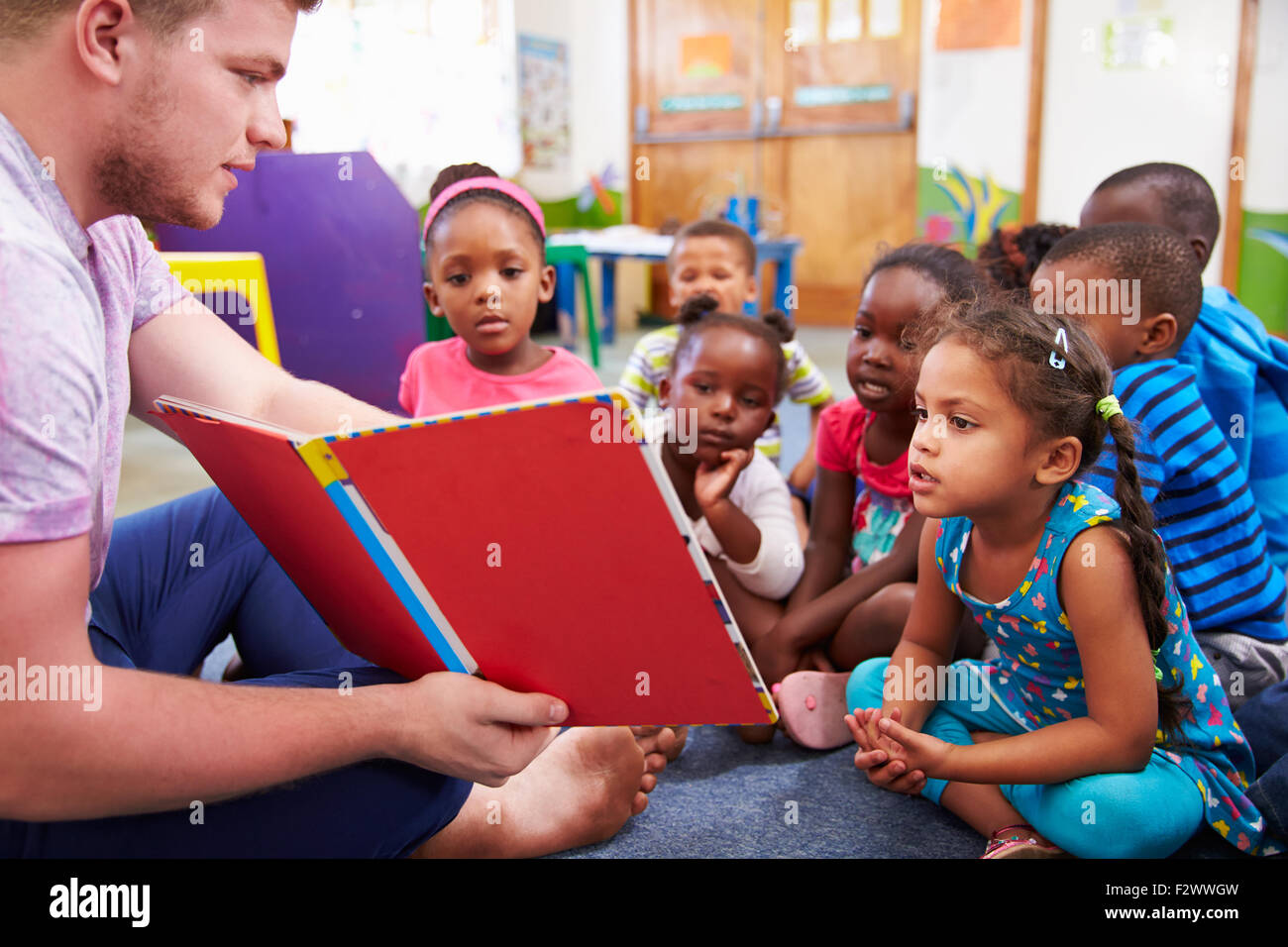 Freiwilliger Lehrer lesen zu einer Klasse von Vorschul-Kinder Stockfoto