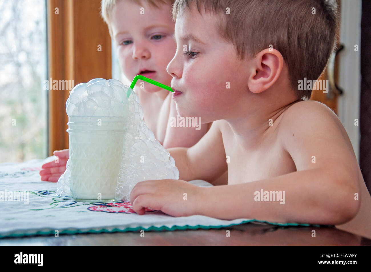 Junge Seifenblasen Milch in ein Glas mit Strohhalm Stockfoto