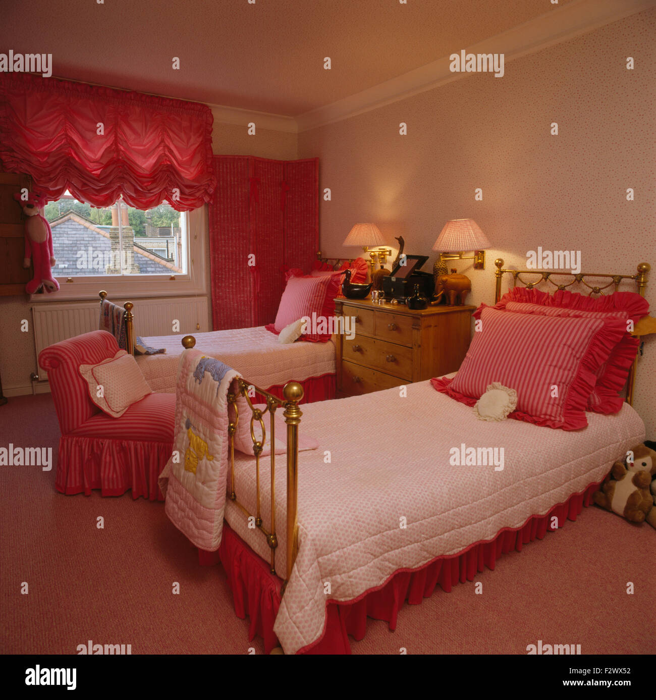 Hell rosa Schwalbenschwanz Blind am Fenster der neunziger Jahre mit rosa Kissen auf Messing Einzelbetten Schlafzimmer Stockfoto