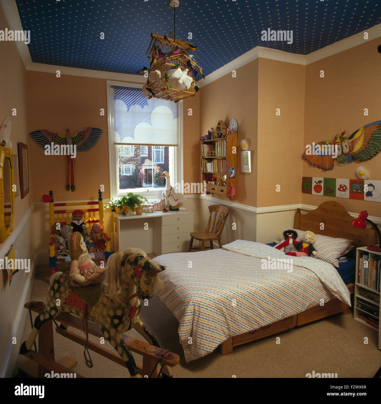 Schaukelpferd und chinesische Papier Drachen in neunziger Jahre Kinder-Schlafzimmer mit gemusterten Rollo am Fenster Stockfoto
