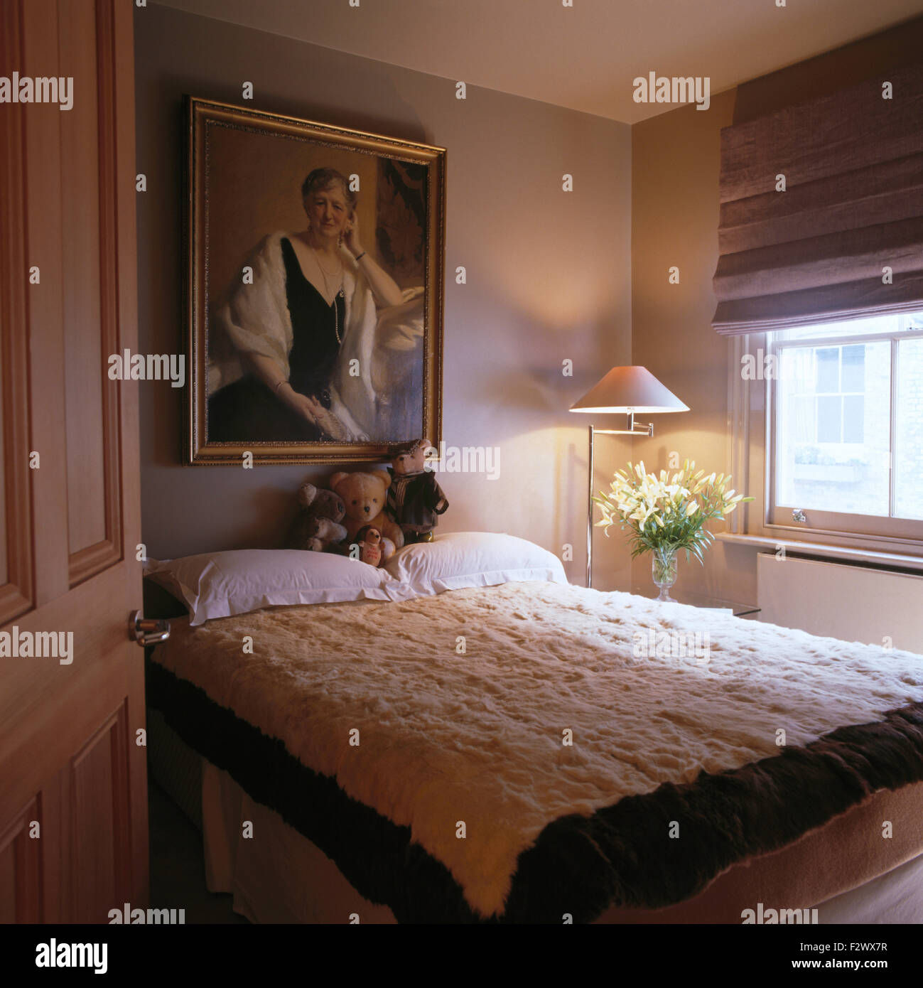 Kunstfell eingefasst weißes Fell Abdeckung auf blass grau Wohnung Schlafzimmer-Bett mit einem grauen Rollo am Fenster Stockfoto