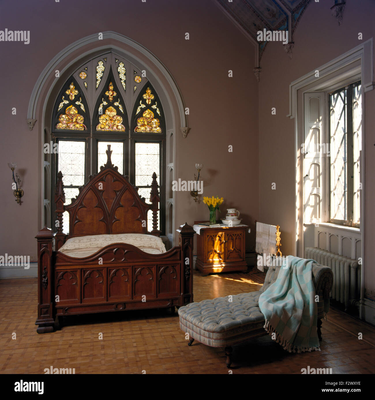 Glasmalerei-Fenster über Gotik Bett der achtziger Jahre in umgebauten Kirche Schlafzimmer Stockfoto