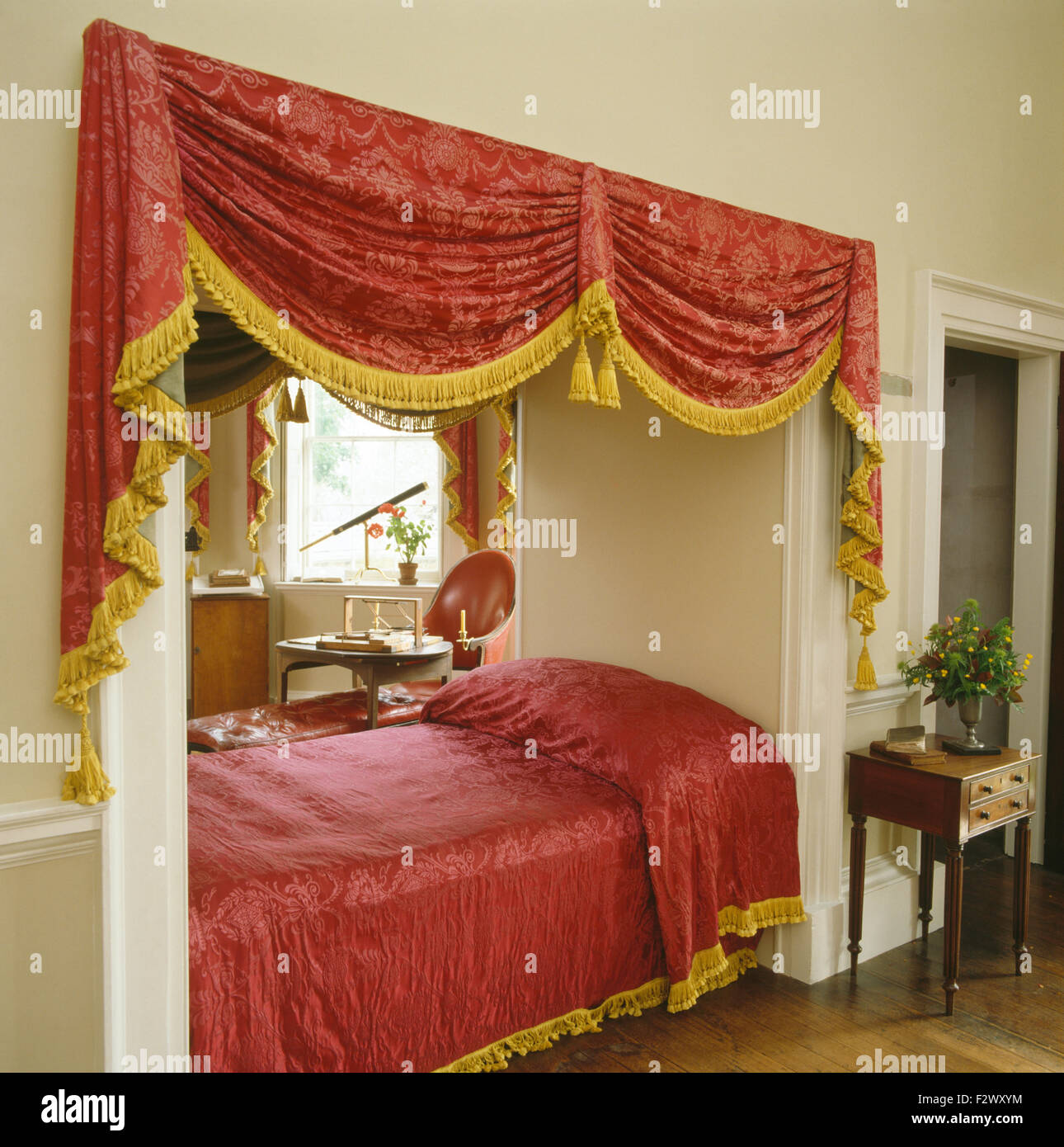 Vergoldet mit Fransen, rote Vorhänge und Bedcoveron Bett in der achtziger Jahre Schlafzimmer Stockfoto
