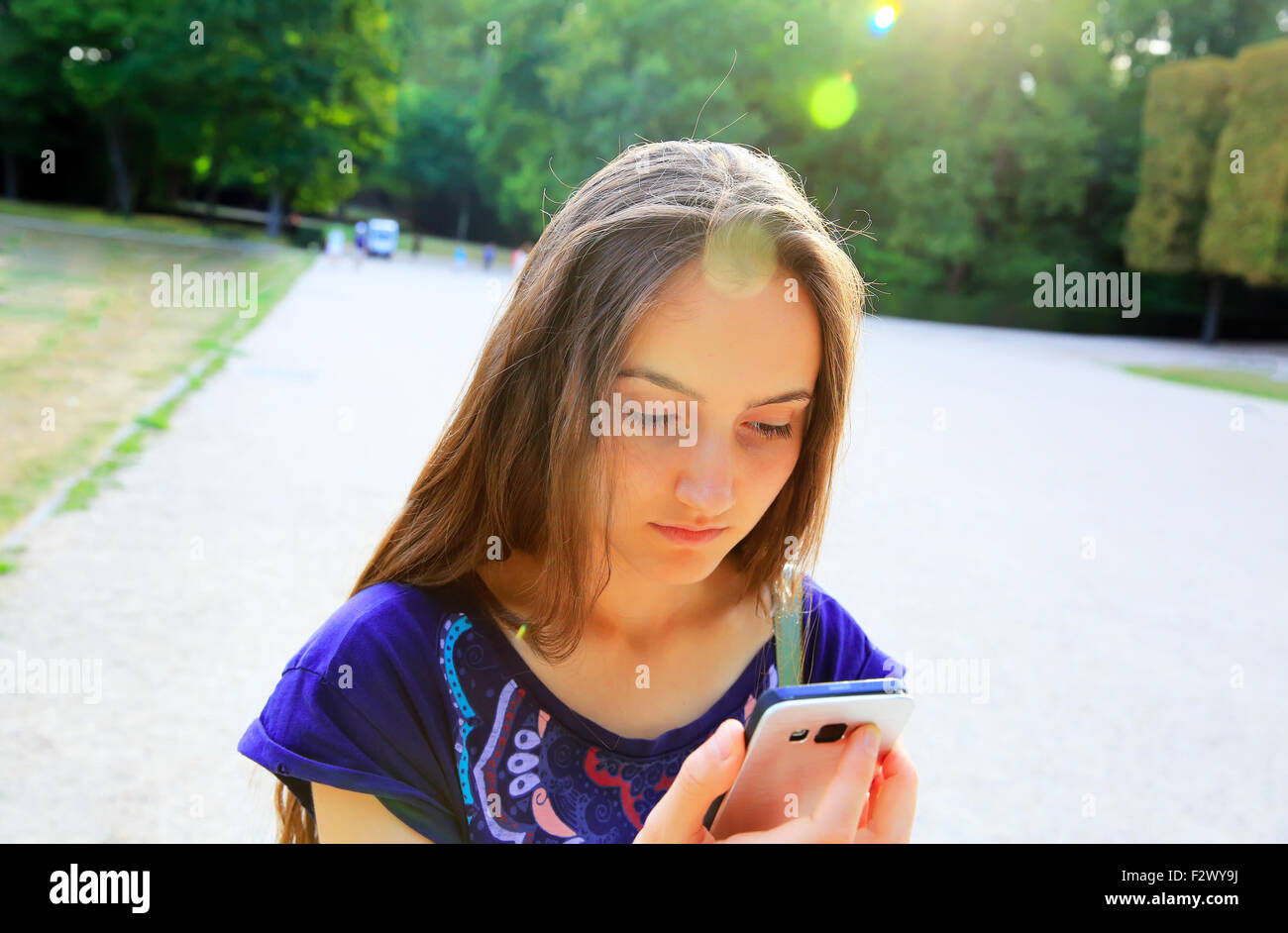 Mädchen mit einem Mobiltelefon liest die Nachricht im park Stockfoto