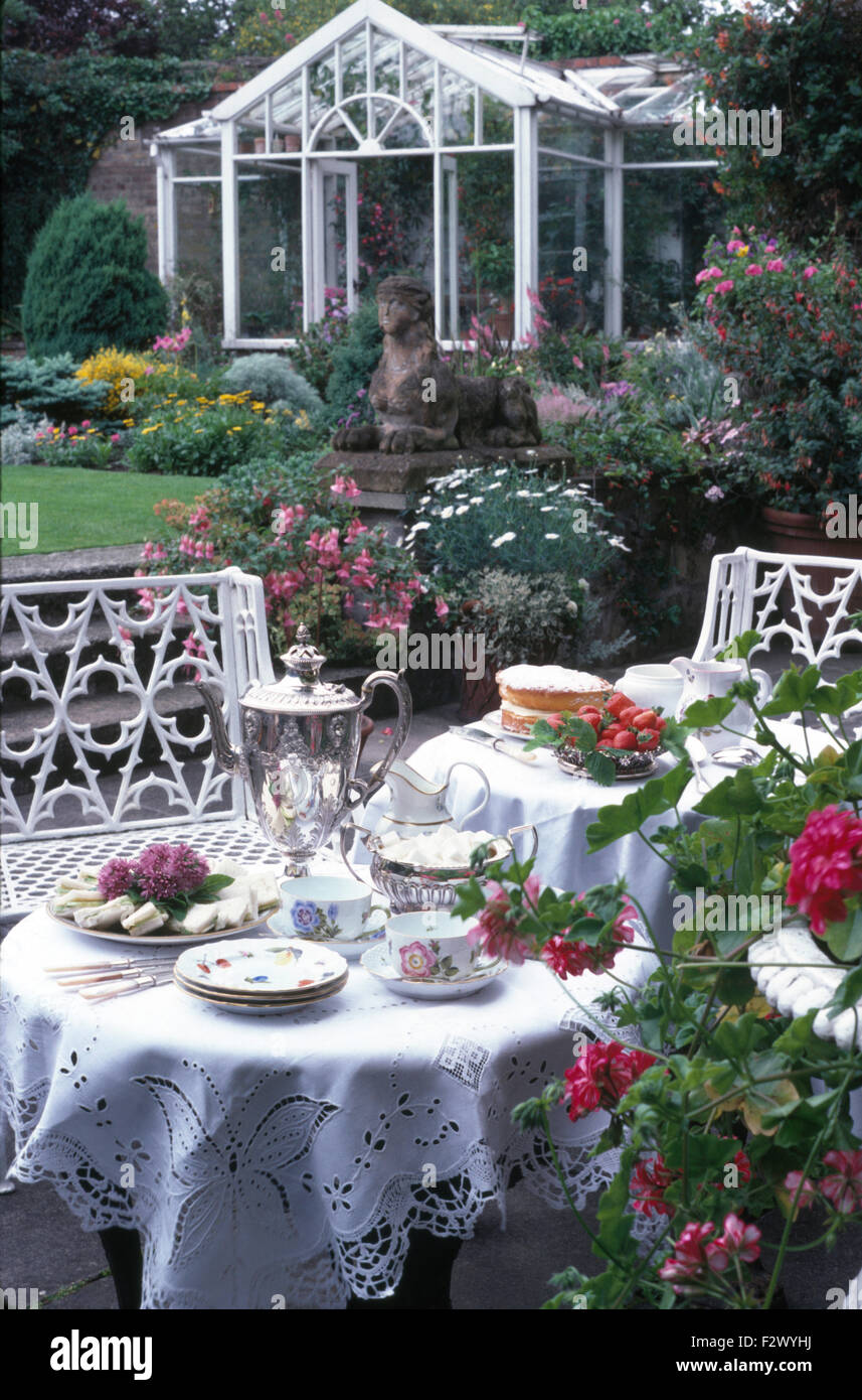 Tisch set für Tee mit weißen abgewetztes Anglaise Tuch und eine silberne Samowar in einem großen Land-Garten im Sommer Stockfoto