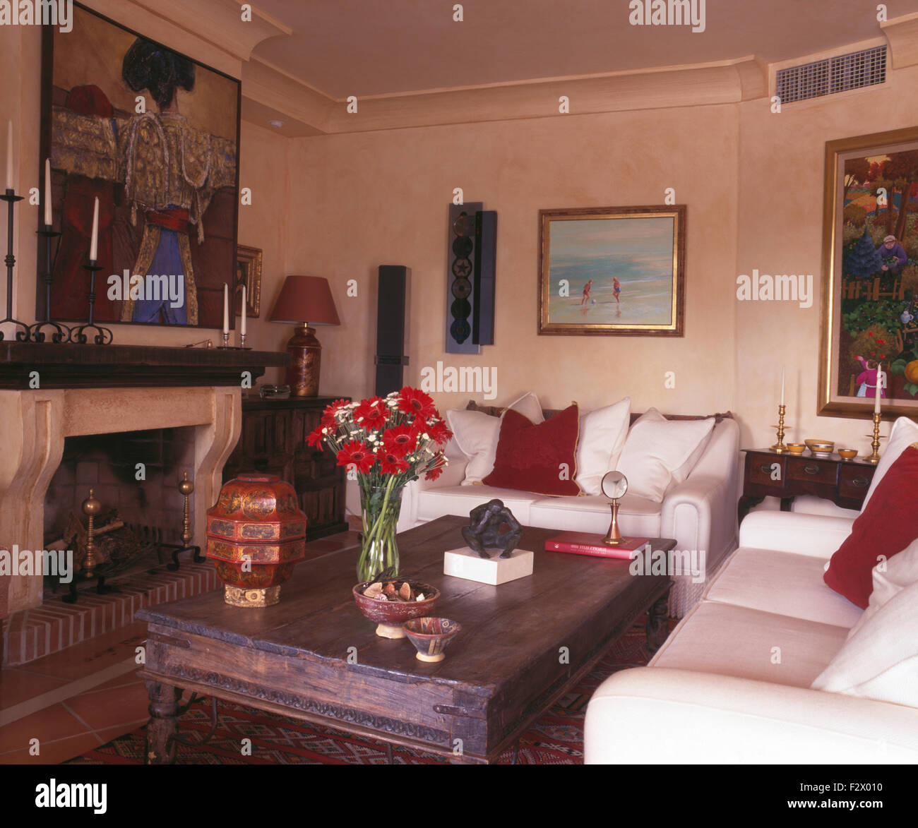 Couchtisch aus Holz indonesischen Stil und weißen Sofas im Wohnzimmer der spanischen Land mit Bild über dem Kamin Stockfoto