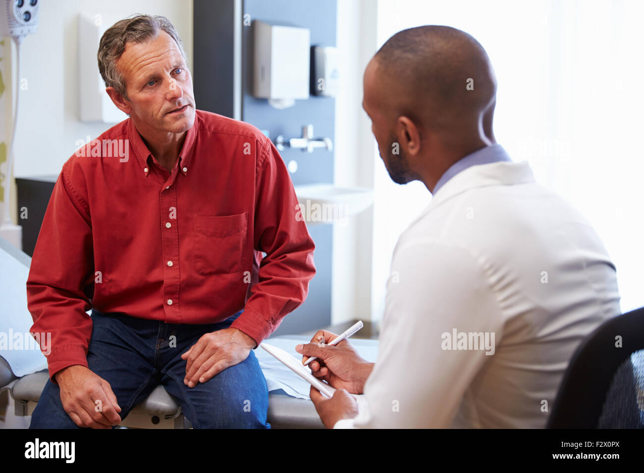 Männlicher Patient und Arzt haben Beratung im Krankenzimmer Stockfoto