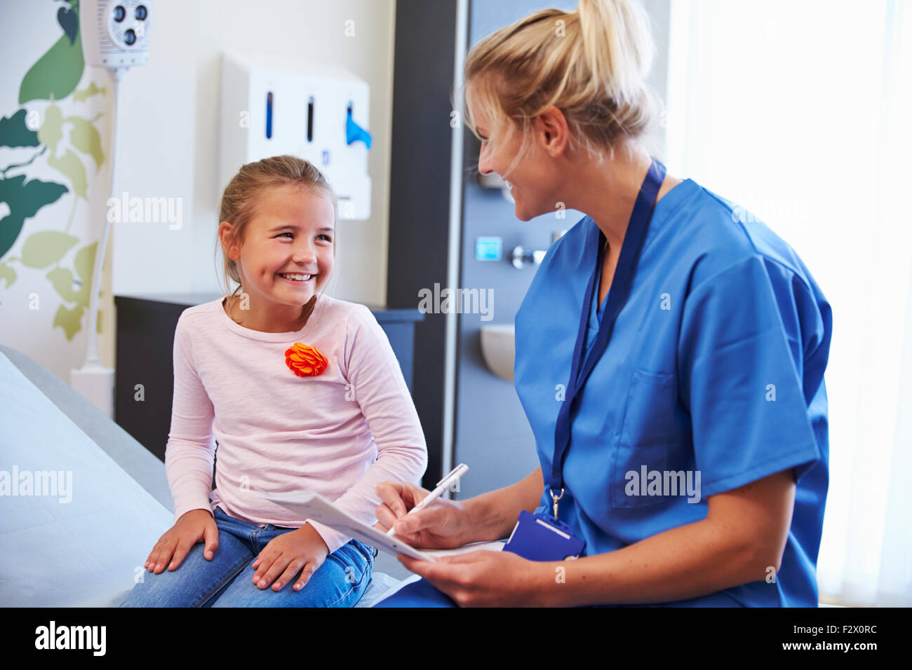 Mädchen im Gespräch mit der Krankenschwester im Krankenzimmer Stockfoto