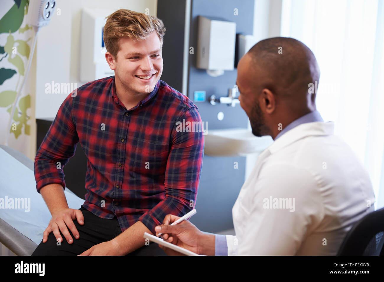Männlicher Patient und Arzt haben Beratung im Krankenzimmer Stockfoto