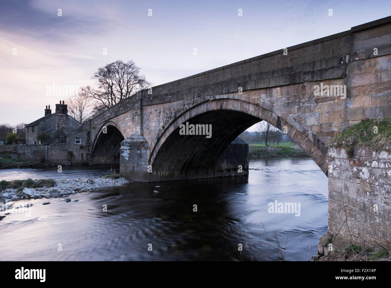 Malerische Aussicht bei Sonnenuntergang, traditionellen, alten, Stein, Straße Brücke über fliessendes Wasser des Flusses Wharfe in der Nähe von Bolton Abbey, Yorkshire Dales, England, UK. Stockfoto