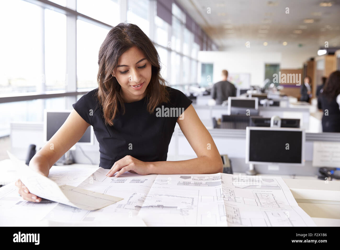 Junge Architektin mit Blaupausen in einem Büro arbeiten Stockfoto