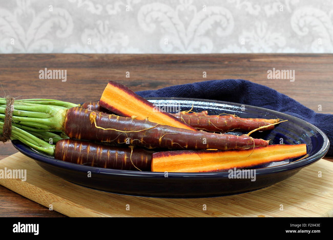 Raw, gewaschen lila Möhren auf einem ovalen Teller. Ganze und aufgeschnittene Karotten Details zu zeigen. Stockfoto