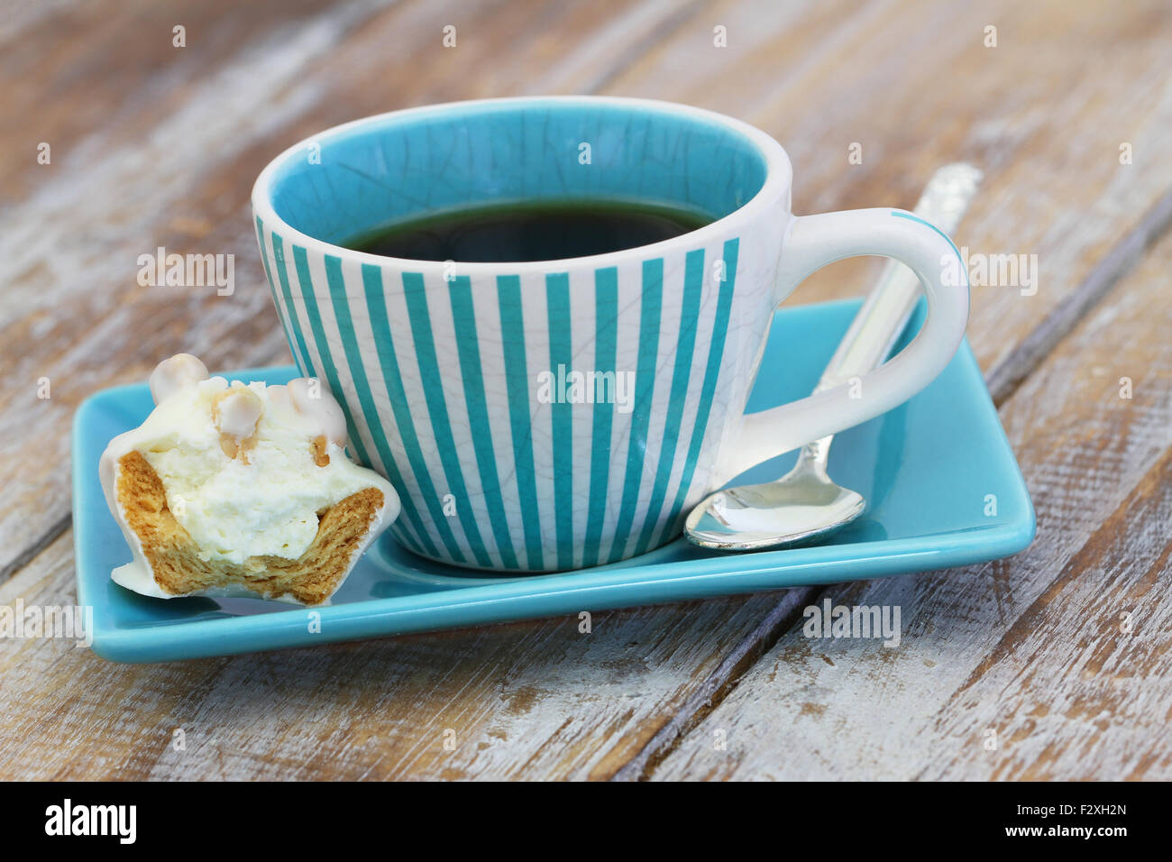 Tasse Kaffee und einem halben cremig Keks auf rustikalen Holzoberfläche Stockfoto