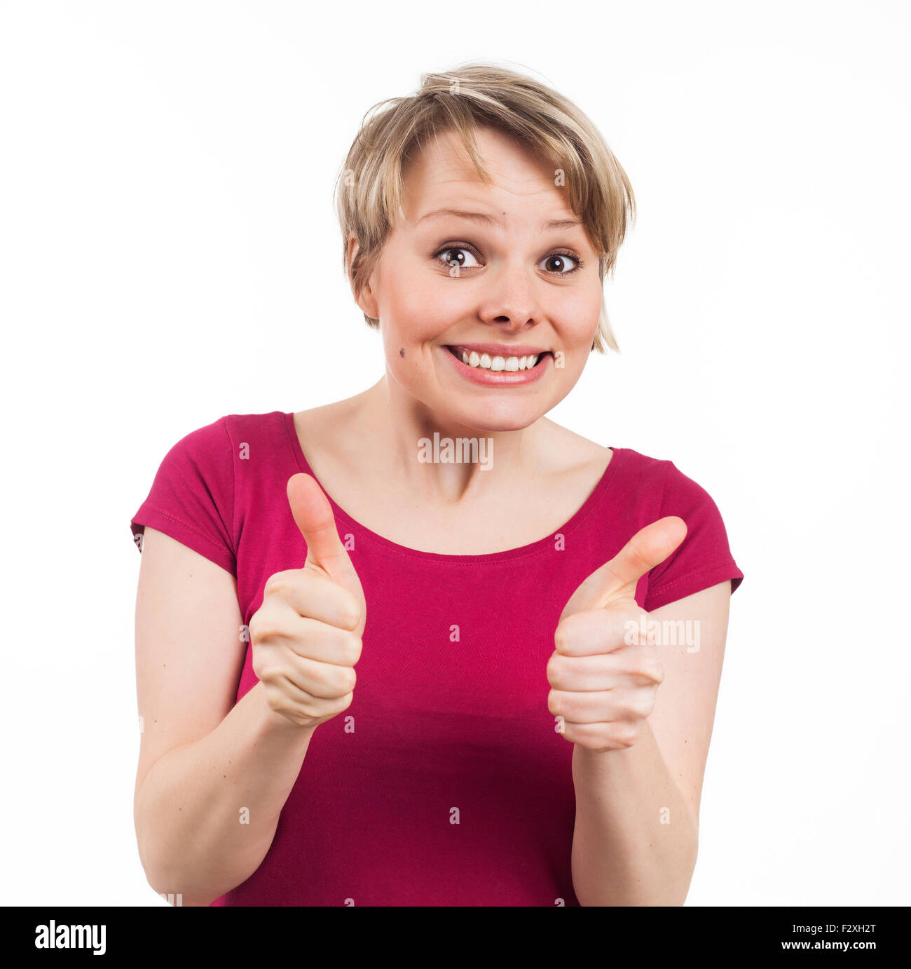 Junge Frau zeigt ihre Daumen und ein schönes Lächeln, isoliert auf weiß Stockfoto