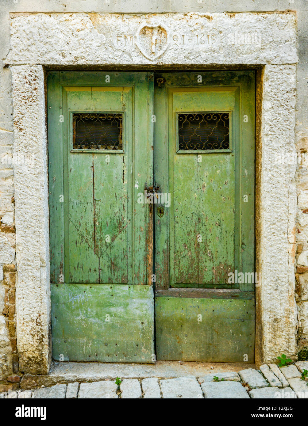 alte grüne zerlumpten schäbige Holztür mit Eisenbarren Stockfoto