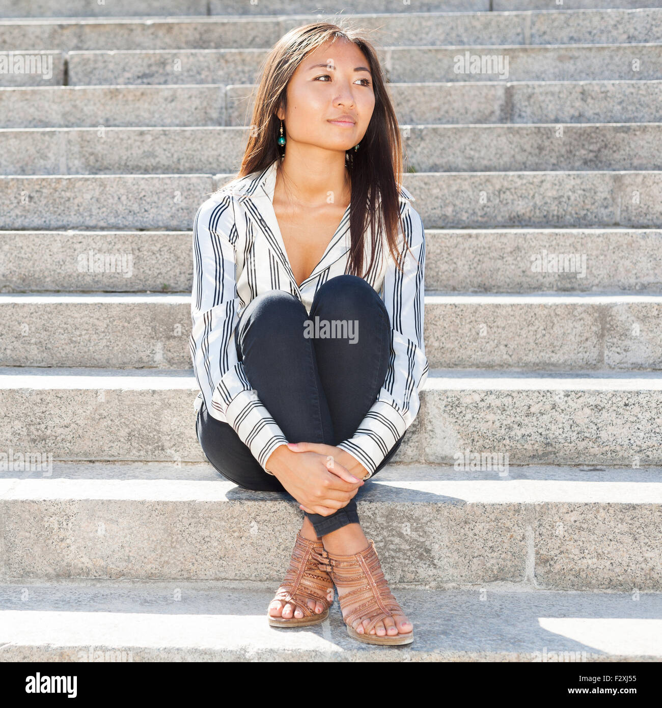 Porträt einer ziemlich asiatische Frau auf Treppen im Freien sitzen und auf der Suche nach etwas Stockfoto